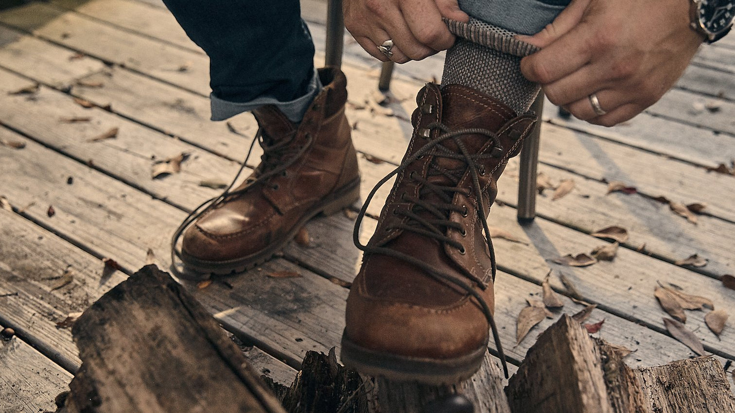 man putting on boots on wood deck