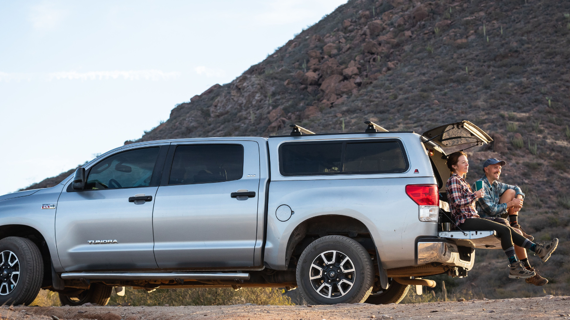 Man and Woman sitting on the bed of a truck